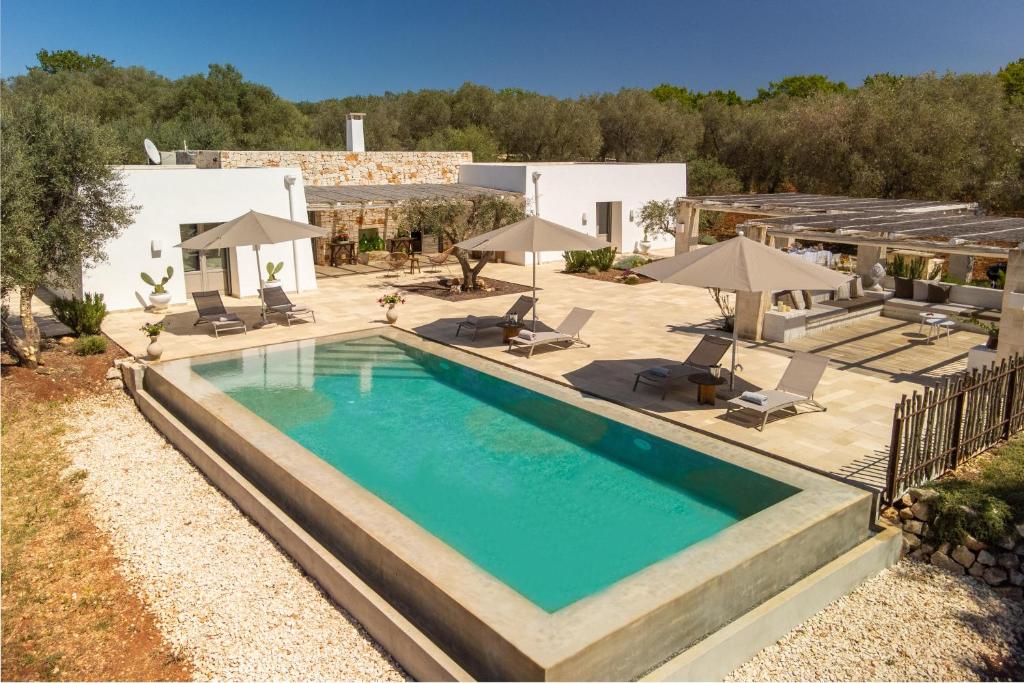 an overhead view of a swimming pool with chairs and umbrellas at Lamia del Bosco con Piscina in Ostuni