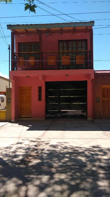 a red building with two garage doors and a balcony at Departamentos PAEZ in Malargüe