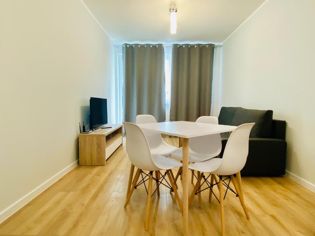 een eetkamer met een witte tafel en witte stoelen bij Apartment Insat IV in Szczecin