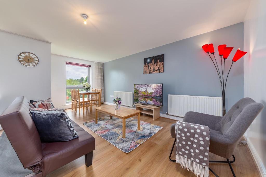 a living room with a couch and a tv at Suites by Rehoboth - Palmers Green - London in London