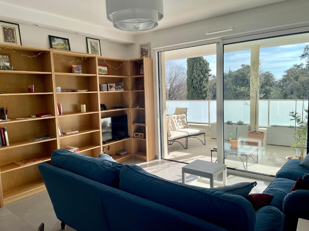 uma sala de estar com um sofá azul e prateleiras de livros em Superbe appartement T3 proche de la garrigue em Castries