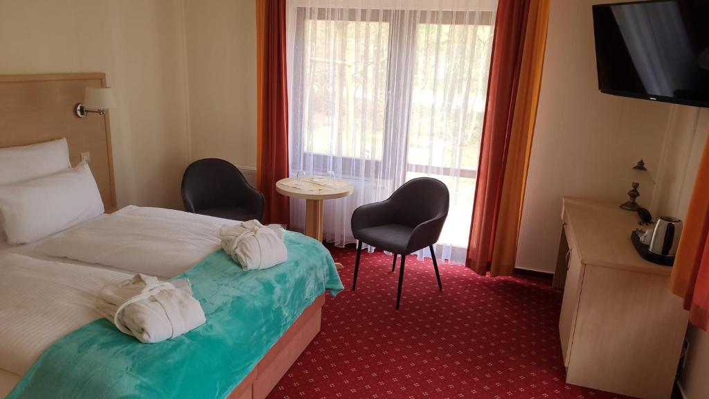 a hotel room with a bed and two chairs and a window at Hubertus in Perleberg
