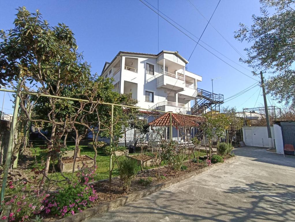 un edificio blanco con un jardín delante de él en Villa Osmani en Durrës