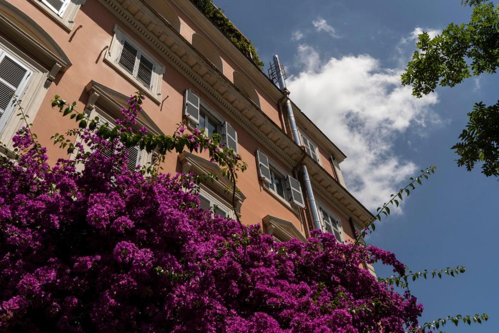 un edificio con flores púrpuras delante de él en Hotel Casa Valdese Roma en Roma