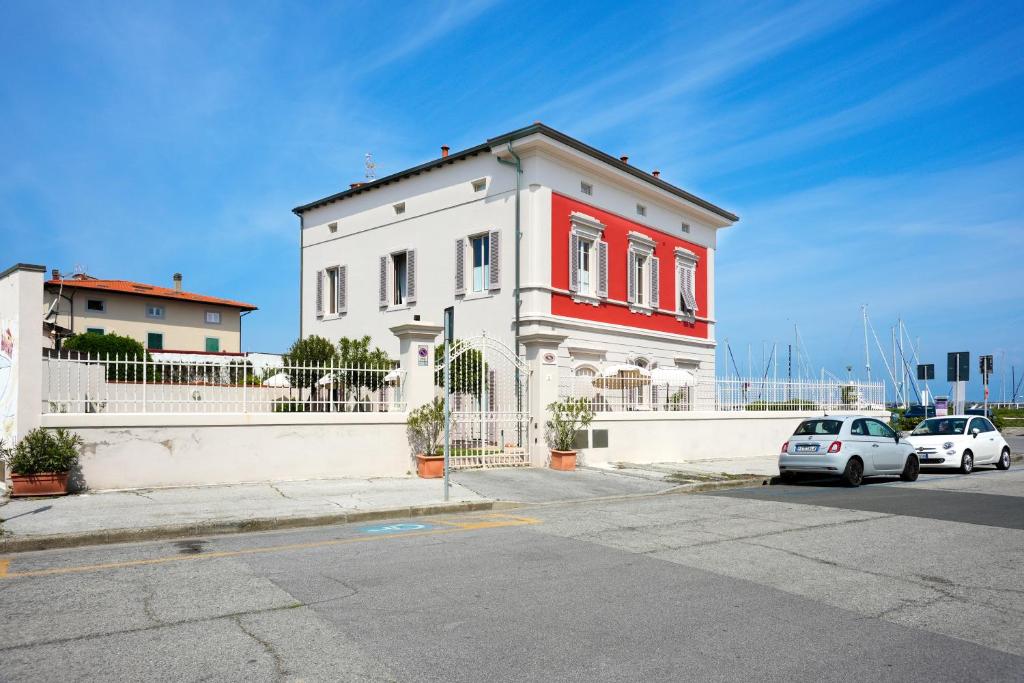 a white and red house with cars parked in front of it at Villino Ermione in Marina di Pisa