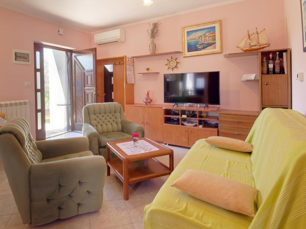 ein Wohnzimmer mit einem Sofa und einem TV in der Unterkunft Apartment Laganis in Plovanija