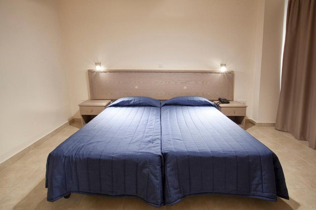 a bedroom with a blue bed with two night stands at Makronisos Village in Ayia Napa
