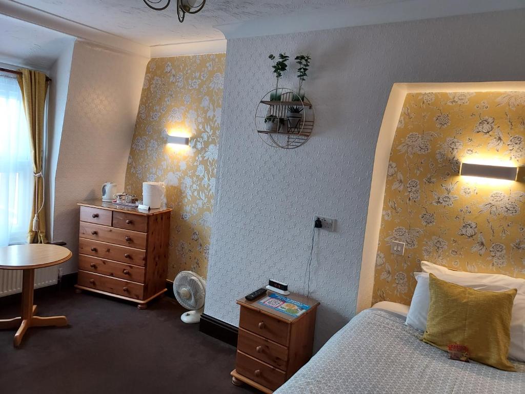 a bedroom with a bed and a dresser and a table at Maluth Lodge in Great Yarmouth