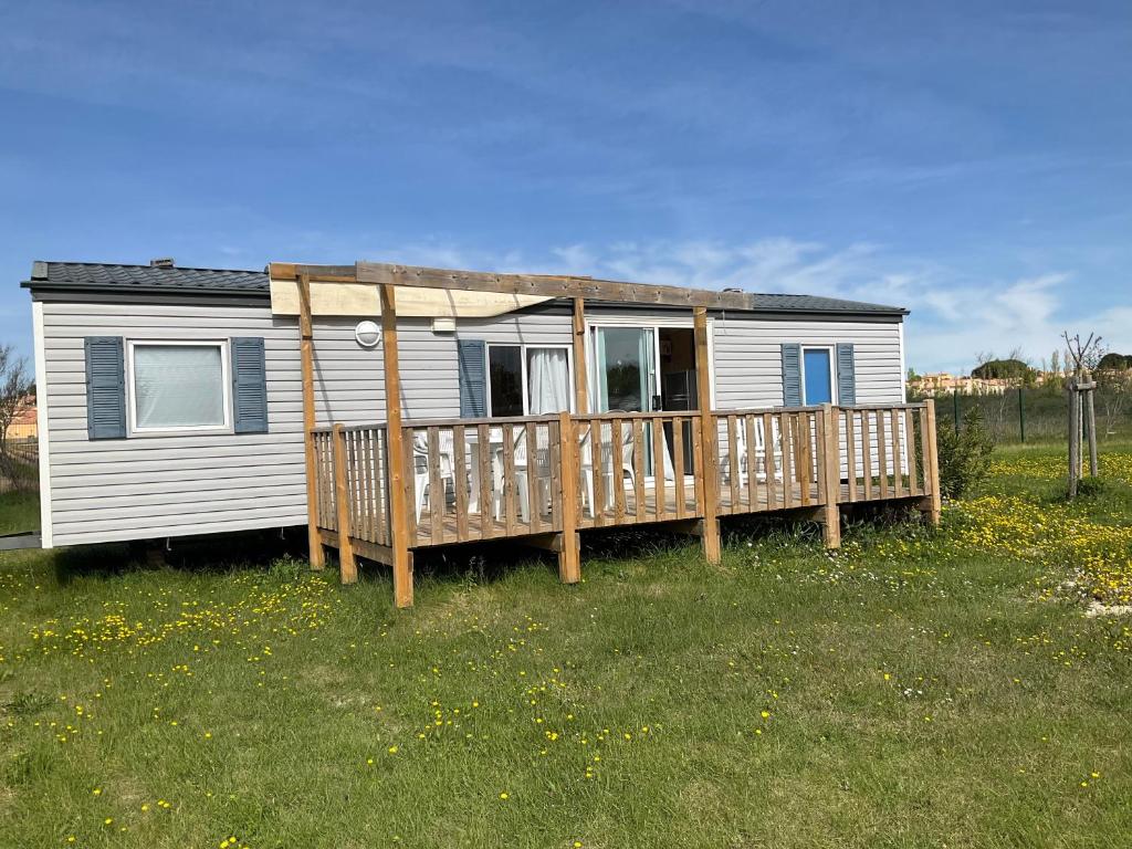 Cette petite maison blanche dispose d'une terrasse en bois. dans l'établissement Mobilhome Coup de Coeur, à Sigean