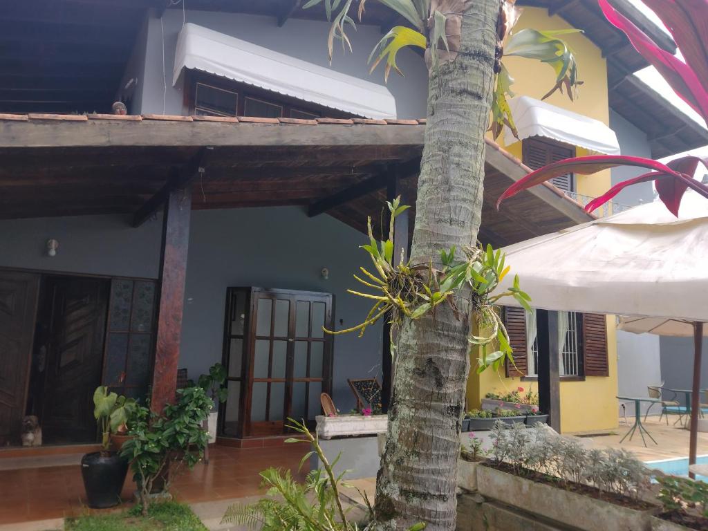una casa con una palmera delante de ella en Hostel Lê Castelle, en Caraguatatuba