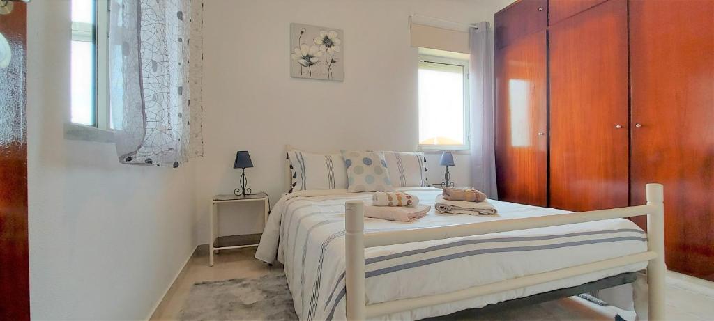 a bedroom with a white bed with a wooden cabinet at Beach&Surf Flat in Aljezur
