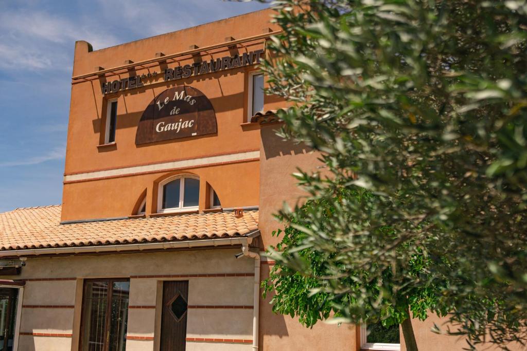 Un bâtiment avec un panneau en haut dans l'établissement Le Mas De Gaujac, à Lézignan-Corbières