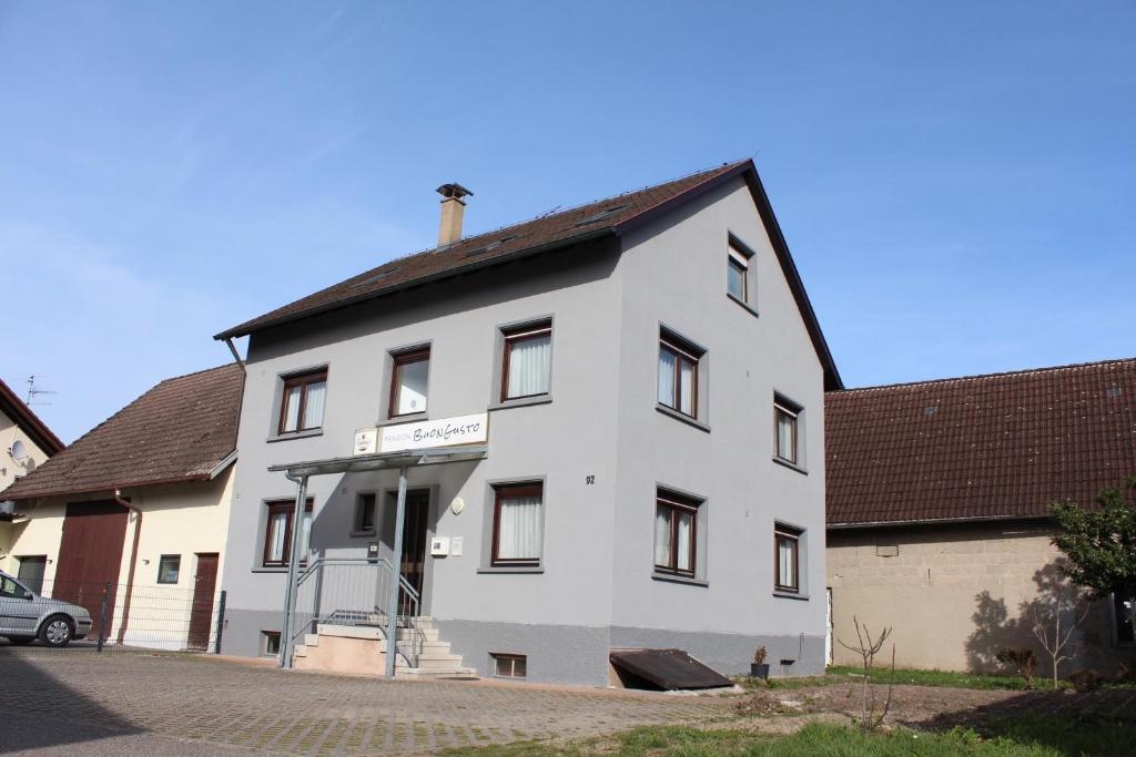 een wit gebouw met een zwart dak bij Pension BuonGusto in Steinmauern