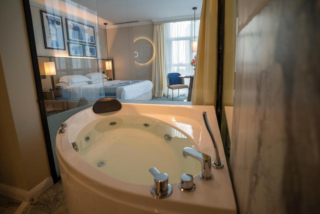 فندق برايم الكورنيش في جدة: حمام مع حوض مع سرير وغرفة نوم