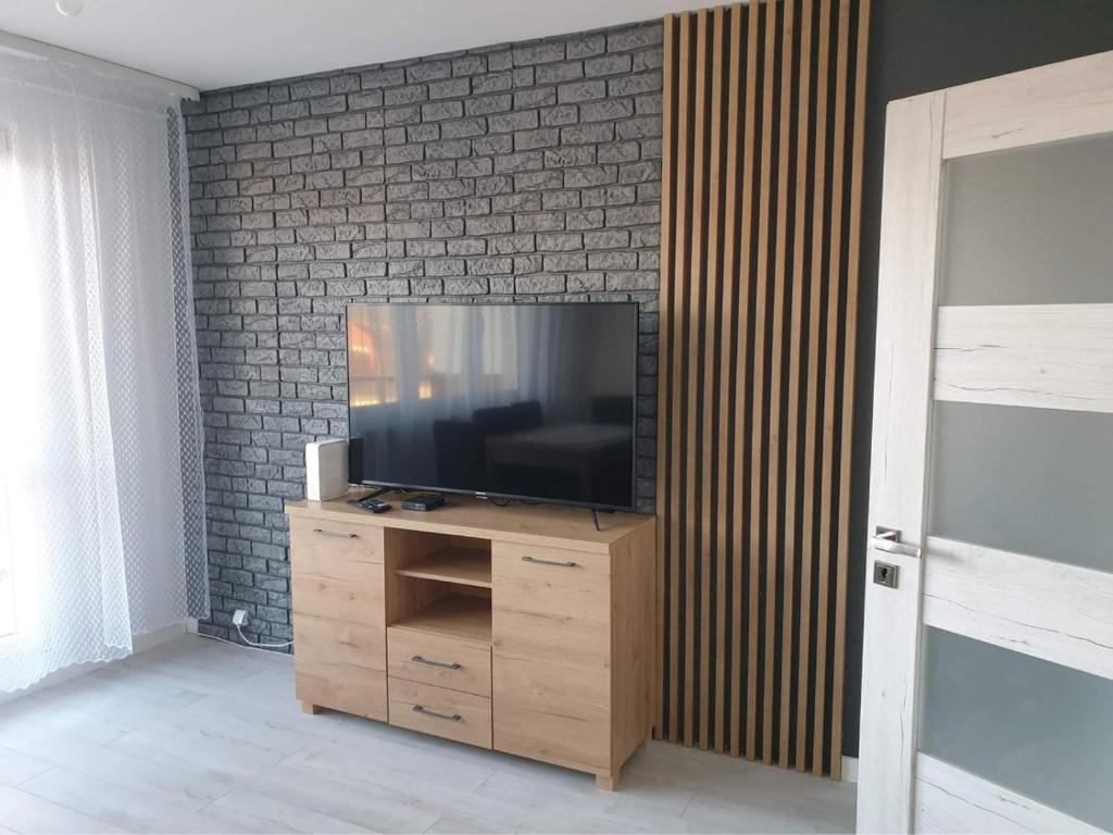 a flat screen tv sitting on top of a wooden cabinet at Apartament Stanley in Iława