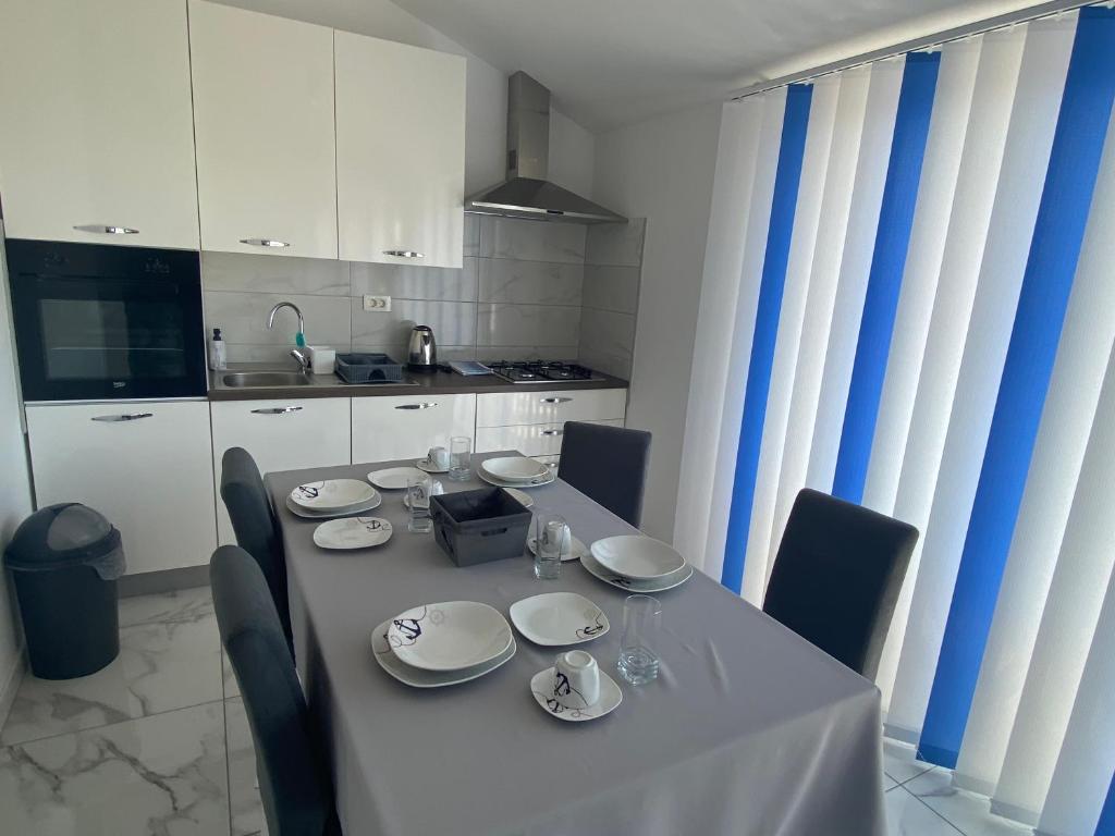 a dining room table with chairs and a white kitchen at Villa Mara in Pula