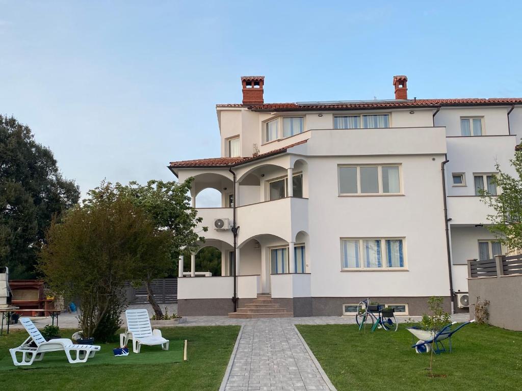 a large white building with a yard with chairs at Villa Mara in Pula