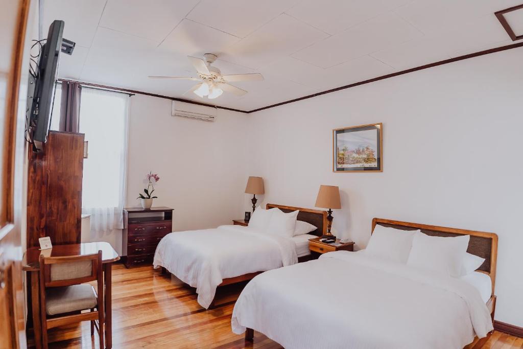 a bedroom with two beds and a ceiling fan at Hotel Dunn Inn in San José