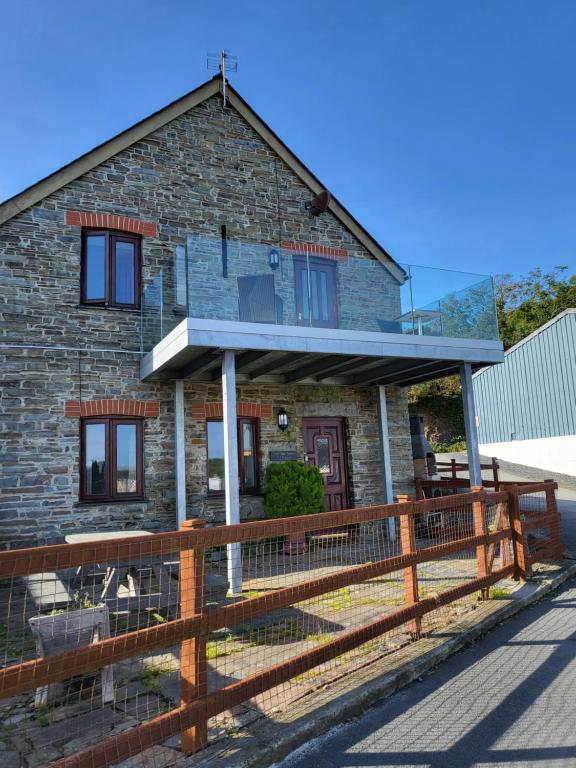 a stone house with a wooden fence in front of it at The Hay Suite in Aberystwyth