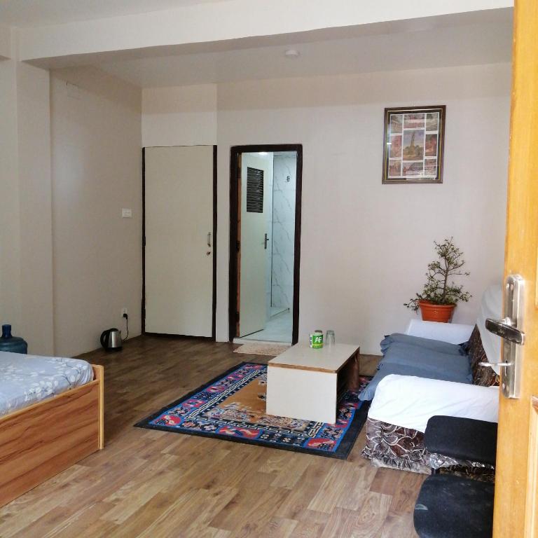 a living room with two beds and a table at newahome in Pātan