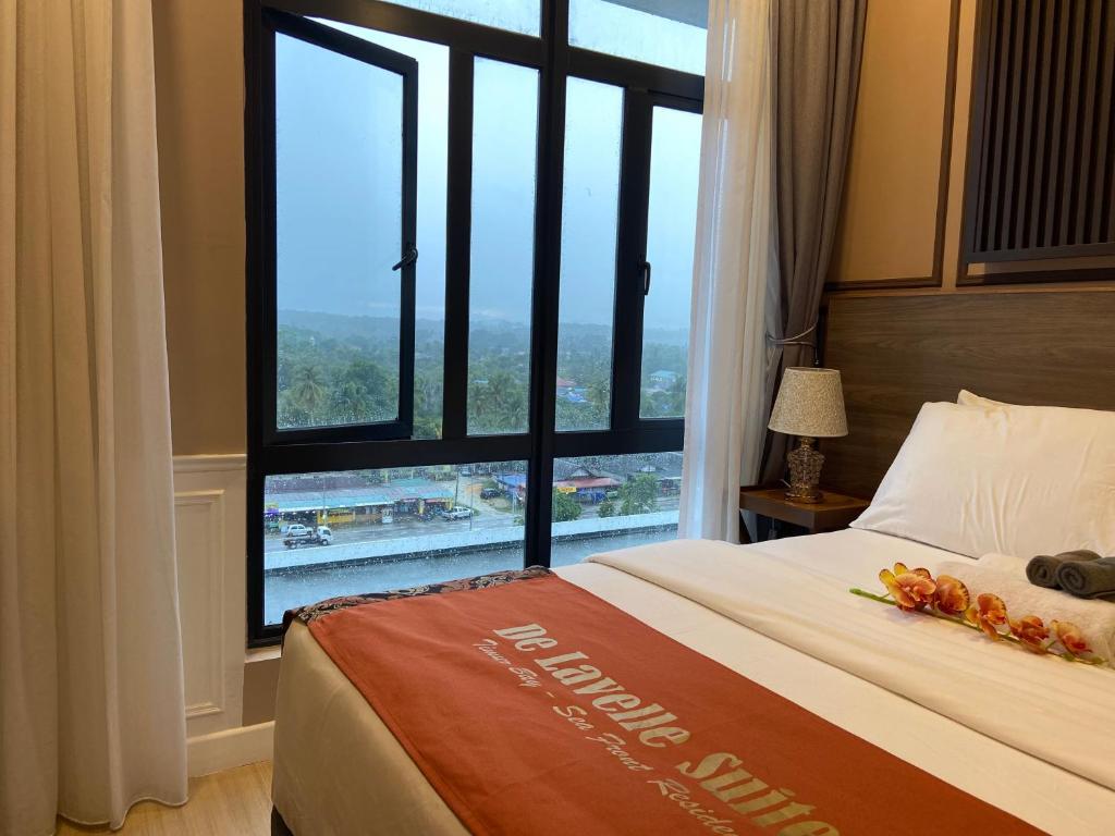 a hotel room with a bed and a large window at De Lavelle Suites @ Timur Bay SeaFront Residence in Kuantan