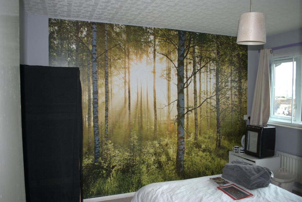 a bedroom with a wall mural of a forest at Dan's House in Manchester