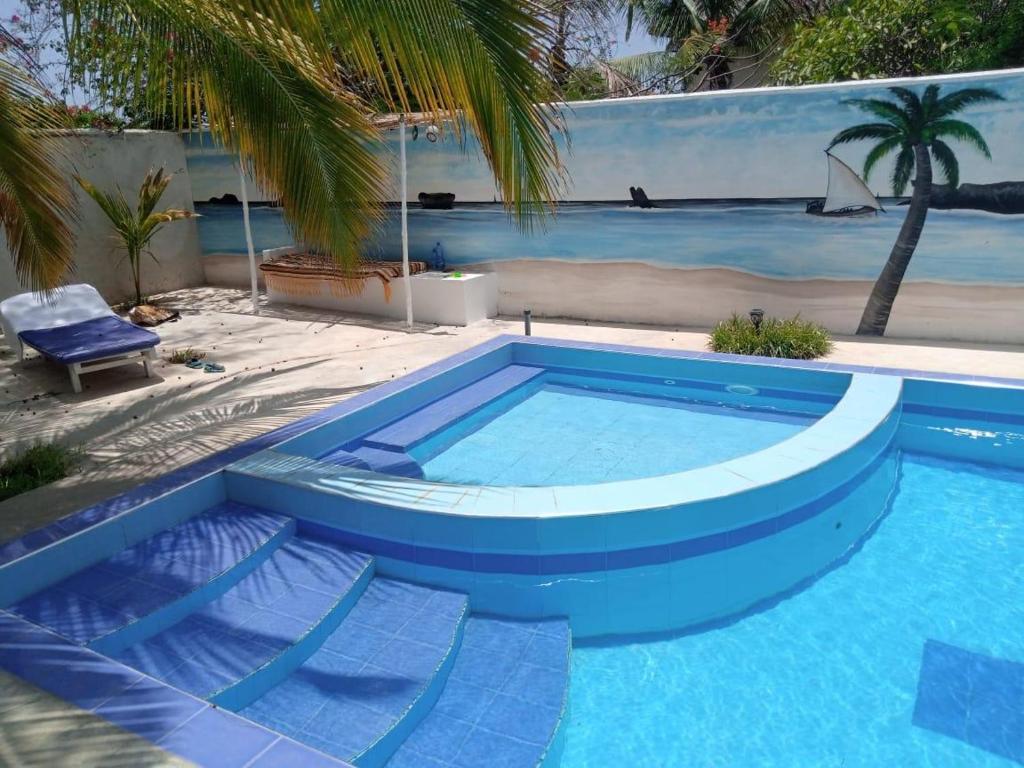 a blue swimming pool with two chairs and a palm tree at Nyumba Tulivu in Watamu