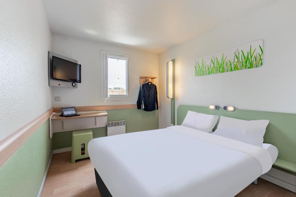 Cette chambre comprend un grand lit et une télévision. dans l'établissement B&B HOTEL Strasbourg Nord Schiltigheim, à Schiltigheim