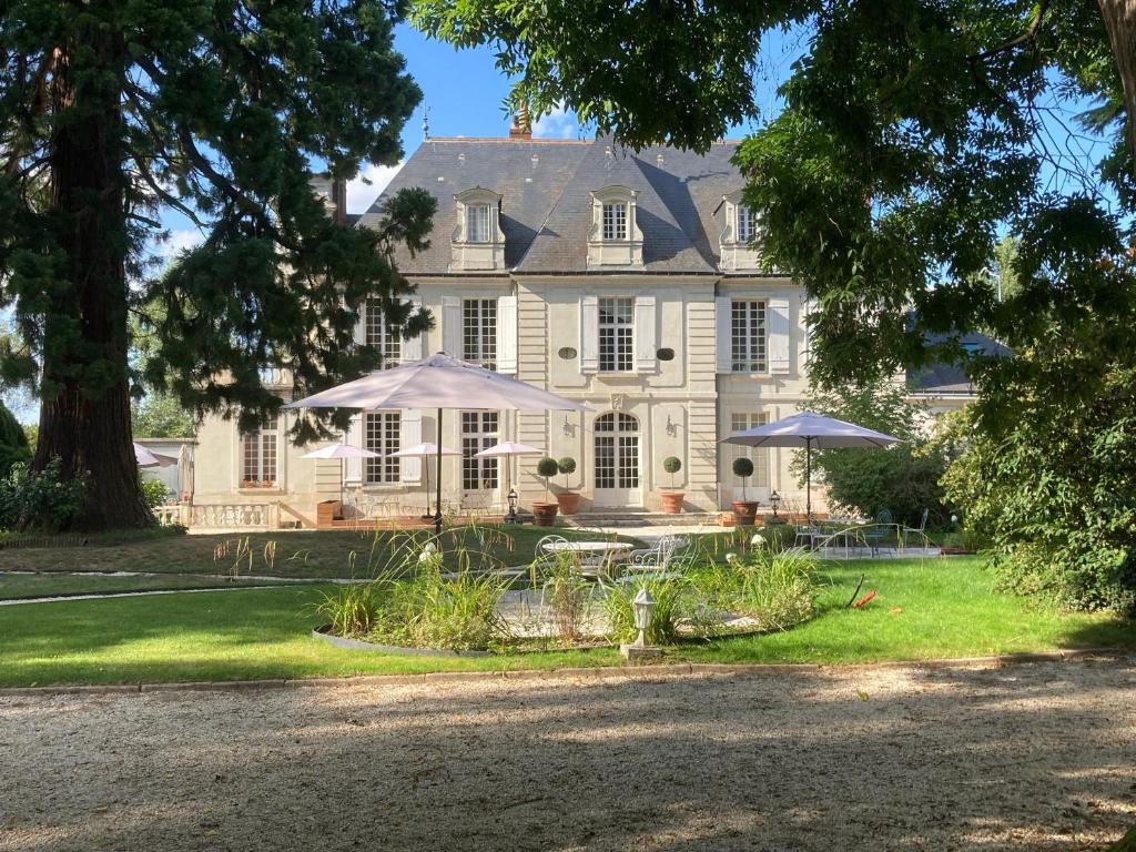 une grande maison blanche avec des parasols en face de celle-ci dans l'établissement Le Clos du Roc, à Montlouis-sur-Loire