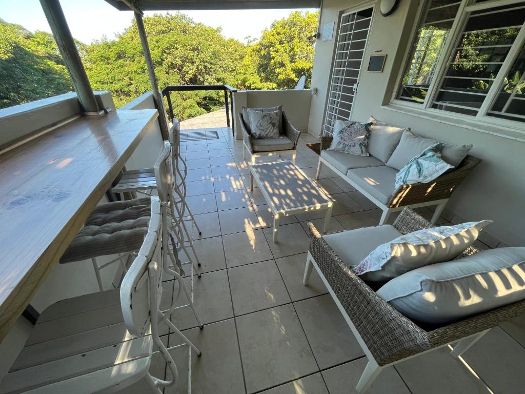 a screened in porch with a couch and chairs at PIGEONWOOD Forest Cottage in Ballito