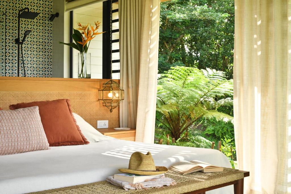 een bed met een hoed op een tafel met een raam bij ChamGaia off-grid eco-villa in Chamarel