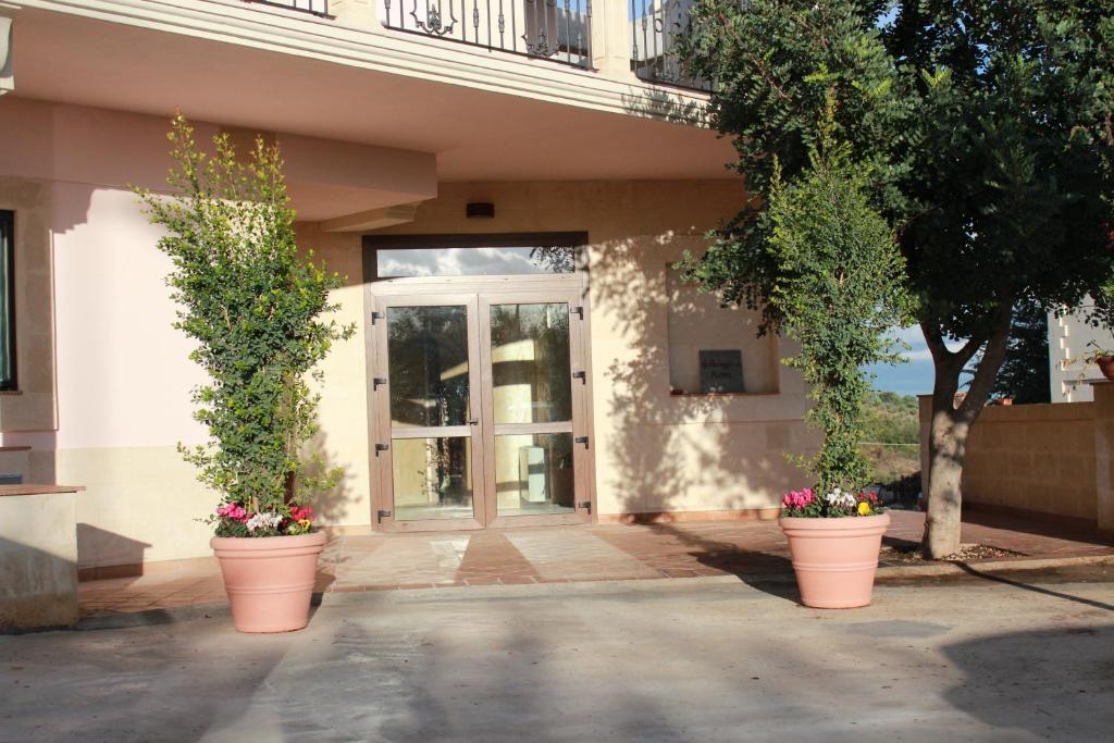 a building with two potted plants in front of a door at Agriturismo Al Passaggio di Pirro in Miglionico