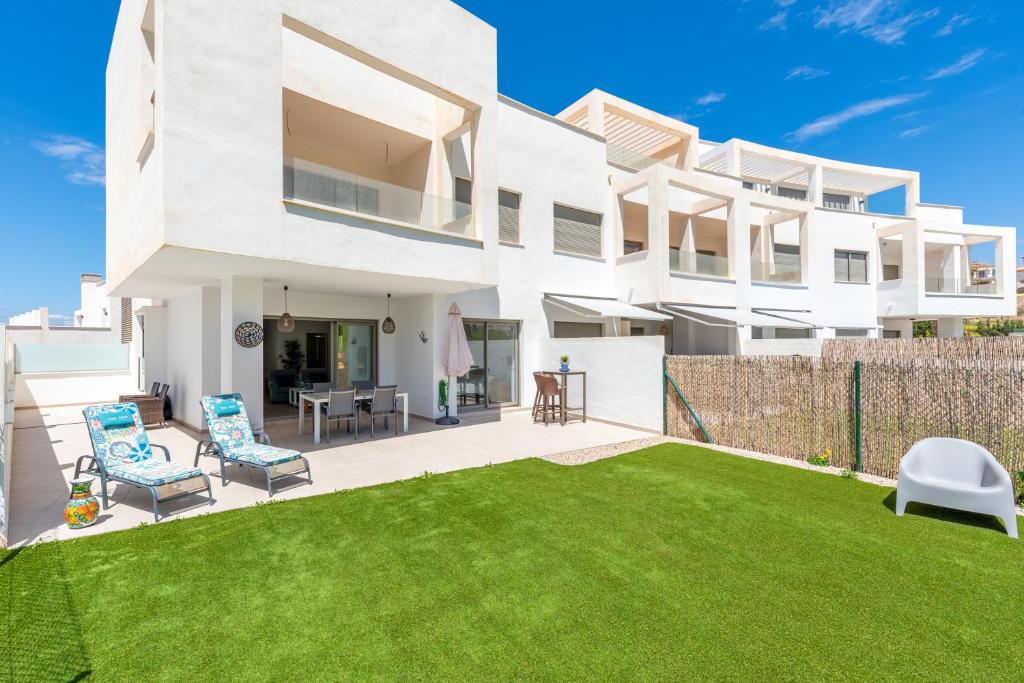 a white house with a lawn in front of it at Baviera Golf Townhouse in Caleta De Velez