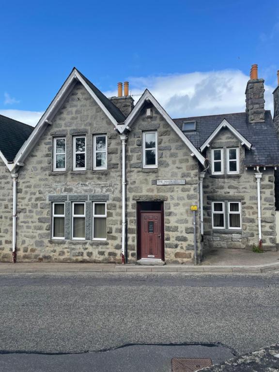 a stone house with a red door on a street at Newsagents Flat in Lairg