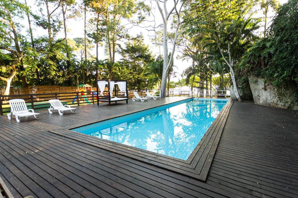 a swimming pool on a wooden deck with chairs and trees at Cabanas Praia Mole Florianopolis in Florianópolis