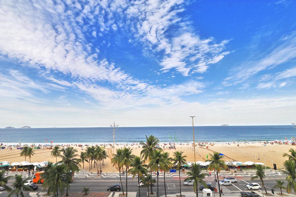 uma vista para uma praia com palmeiras e para o oceano em Rio Spot Atlantica 2440 no Rio de Janeiro