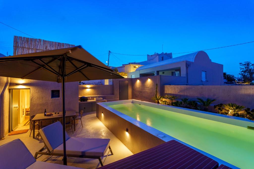 a swimming pool with two chairs and an umbrella at Present Perfect Villa - private pool in Firostefani