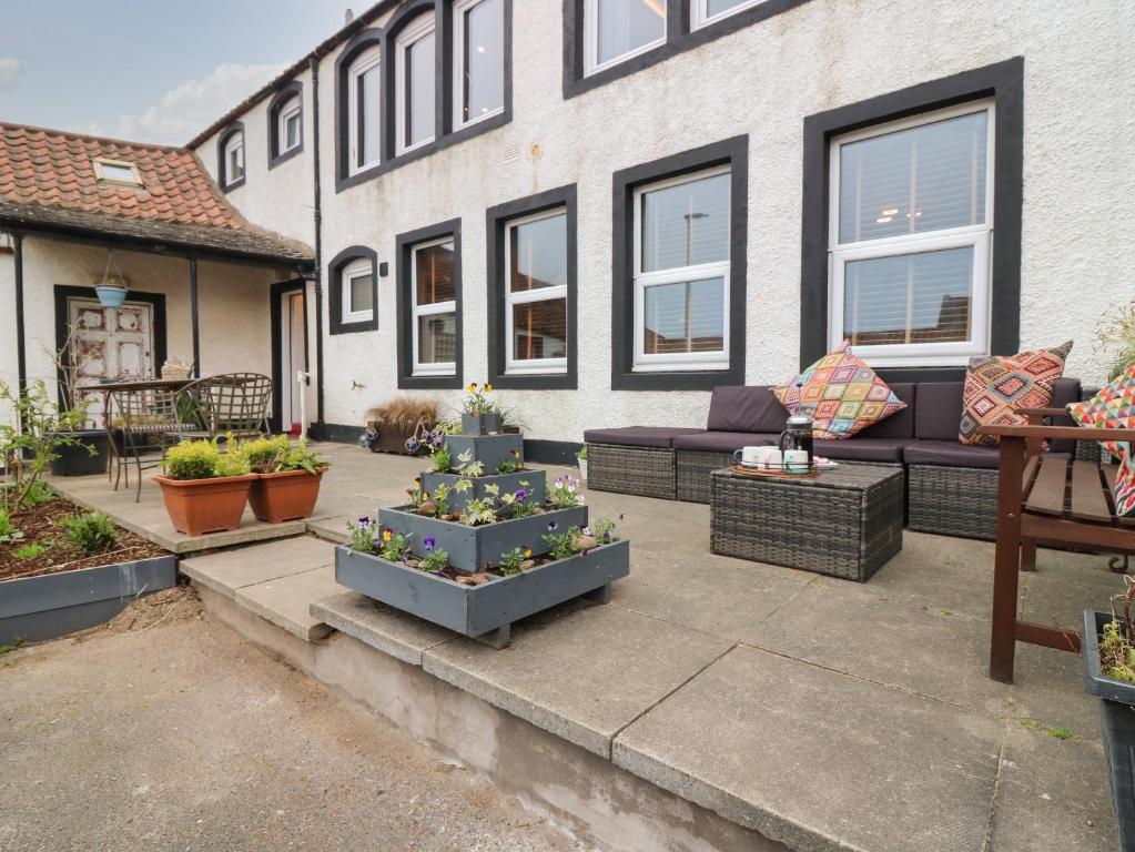 a patio with a couch and some potted plants at Fisher's Rest in Anstruther