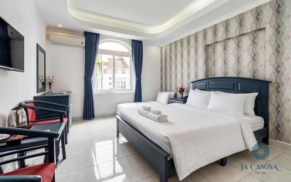 a bedroom with a large bed with blue curtains at La Casona Hotel in Ho Chi Minh City