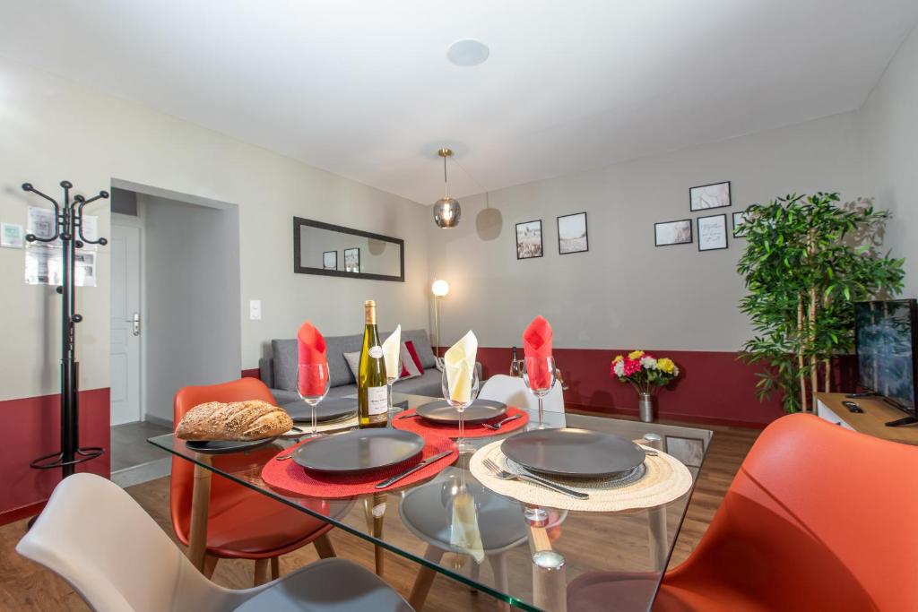 a dining room with a glass table and red chairs at Le Red St Léon : Lit Queen Size * WIFI * Idéal Couple in Colmar