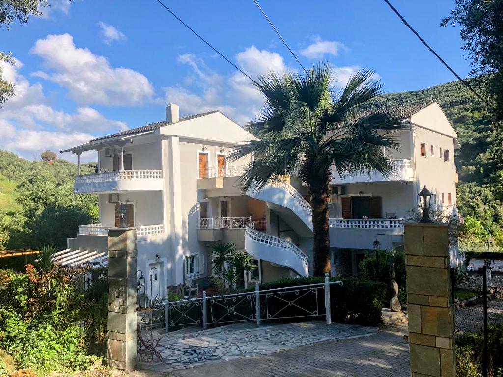 a white house with a palm tree in front of it at Golden Sun in Parga
