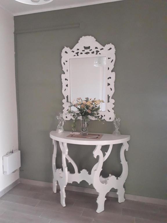 un tavolo bianco con uno specchio e un vaso di fiori sopra di Villa Teresa a Trappeto
