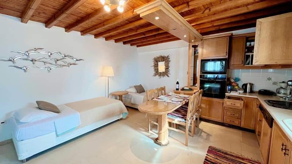 a bedroom with a bed and a kitchen with a table at Casa Paraportiani View Mykonos Town House in Mikonos