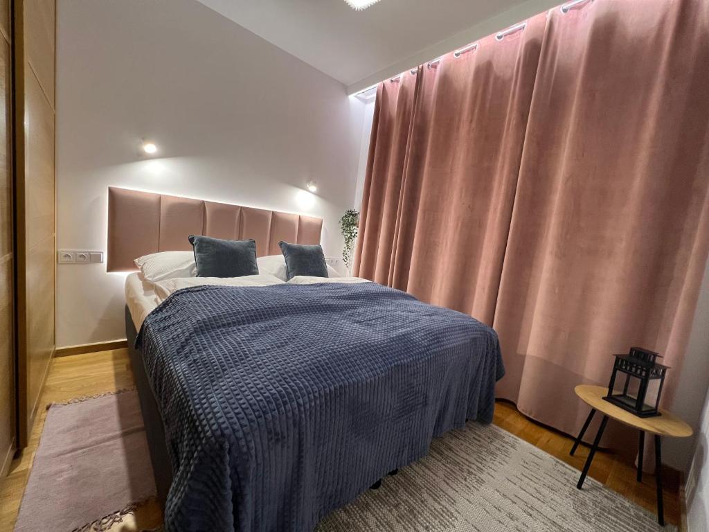 Schlafzimmer mit einem Bett und einem Fenster mit rosa Vorhängen in der Unterkunft Norblin Apart in Warschau