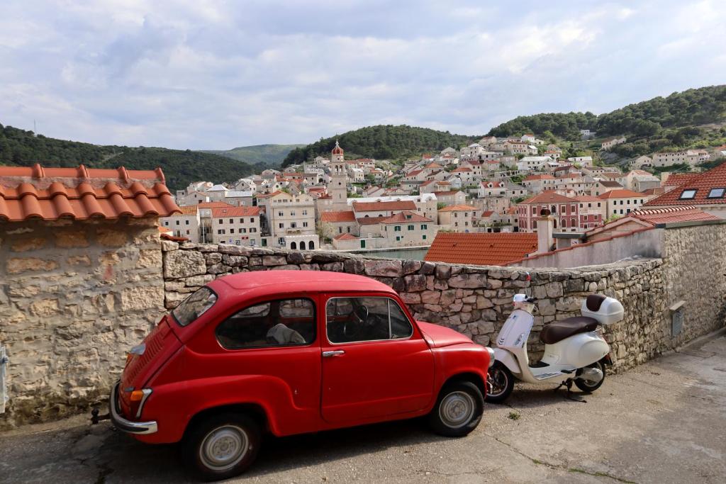 a small red car parked next to a scooter at Apartment Lea in Pučišća