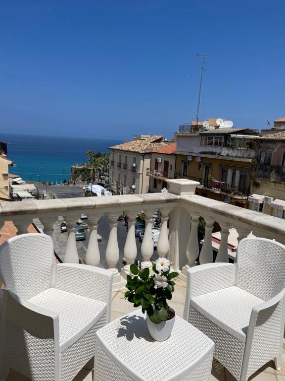 a balcony with white chairs and a vase with flowers at Terrazzo Del Borgo in Tropea