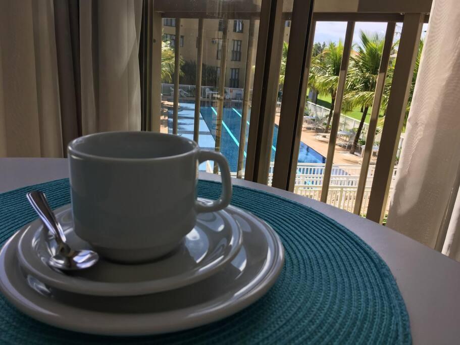 a coffee cup on a table with a view of a pool at Reserva Ecológica do Sahy, Condado in Mangaratiba