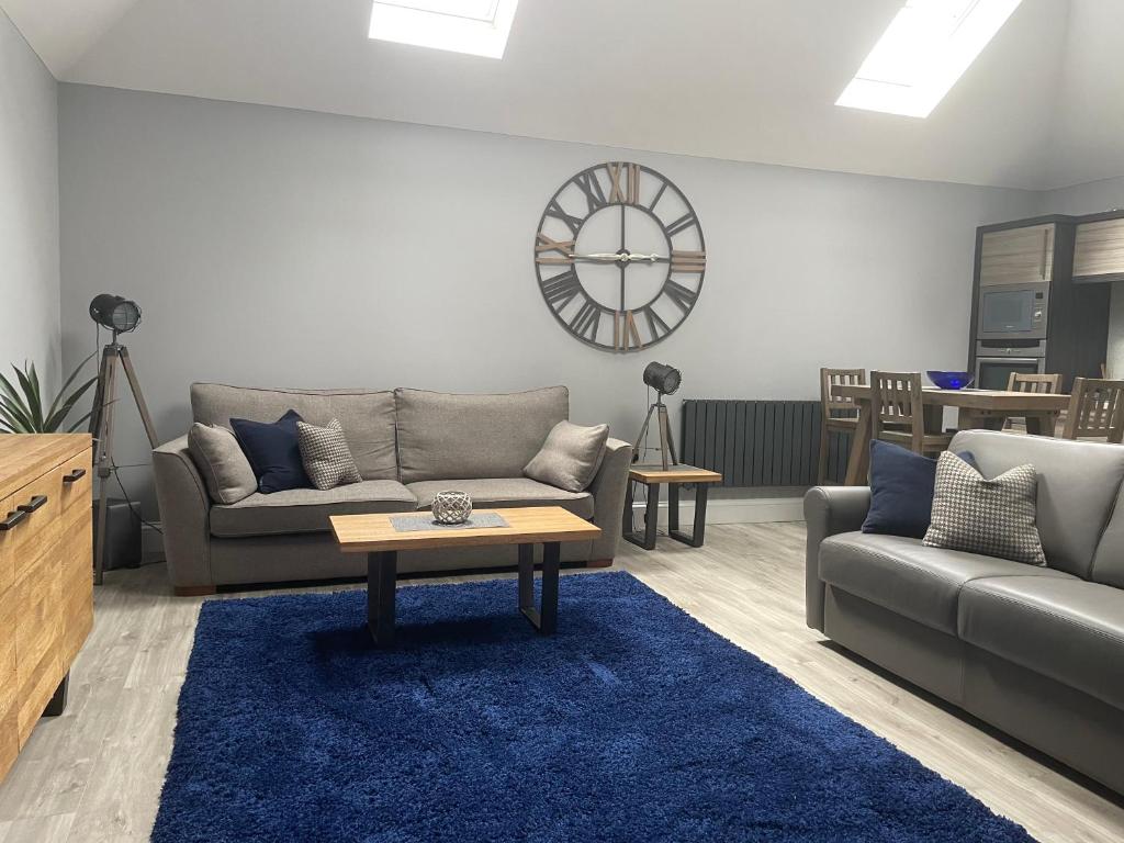 a living room with a couch and a table and a clock at The Store, Luxury modern conversion with open plan living - Sleeps 4 in Wick