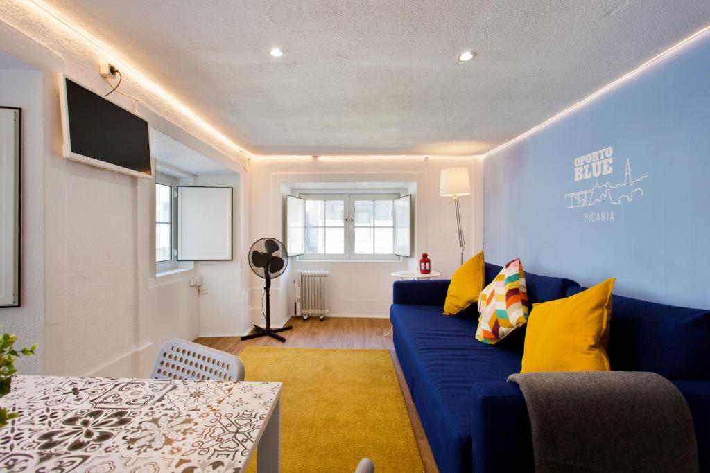 uma sala de estar com um sofá azul e uma mesa em Oporto Blue Picaria - Unique Citycenter Apartment no Porto
