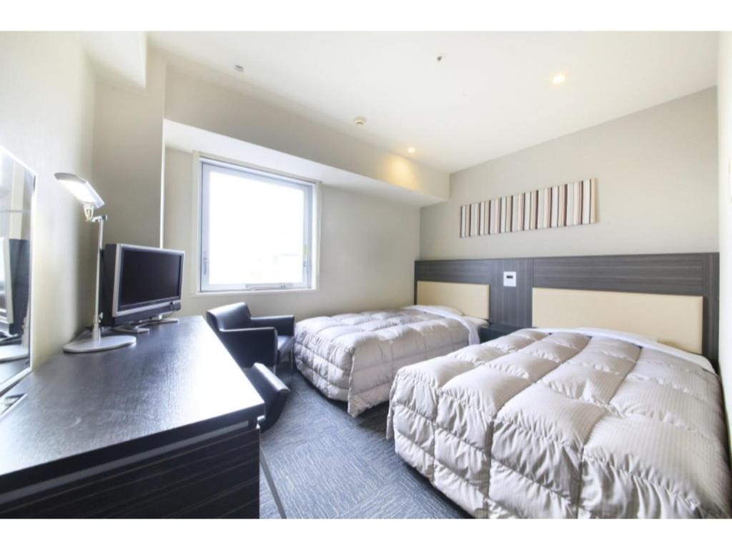um quarto com 2 camas, uma secretária e uma televisão em R&B HOTEL HACHIOJI - Vacation STAY 38820v em Hachioji